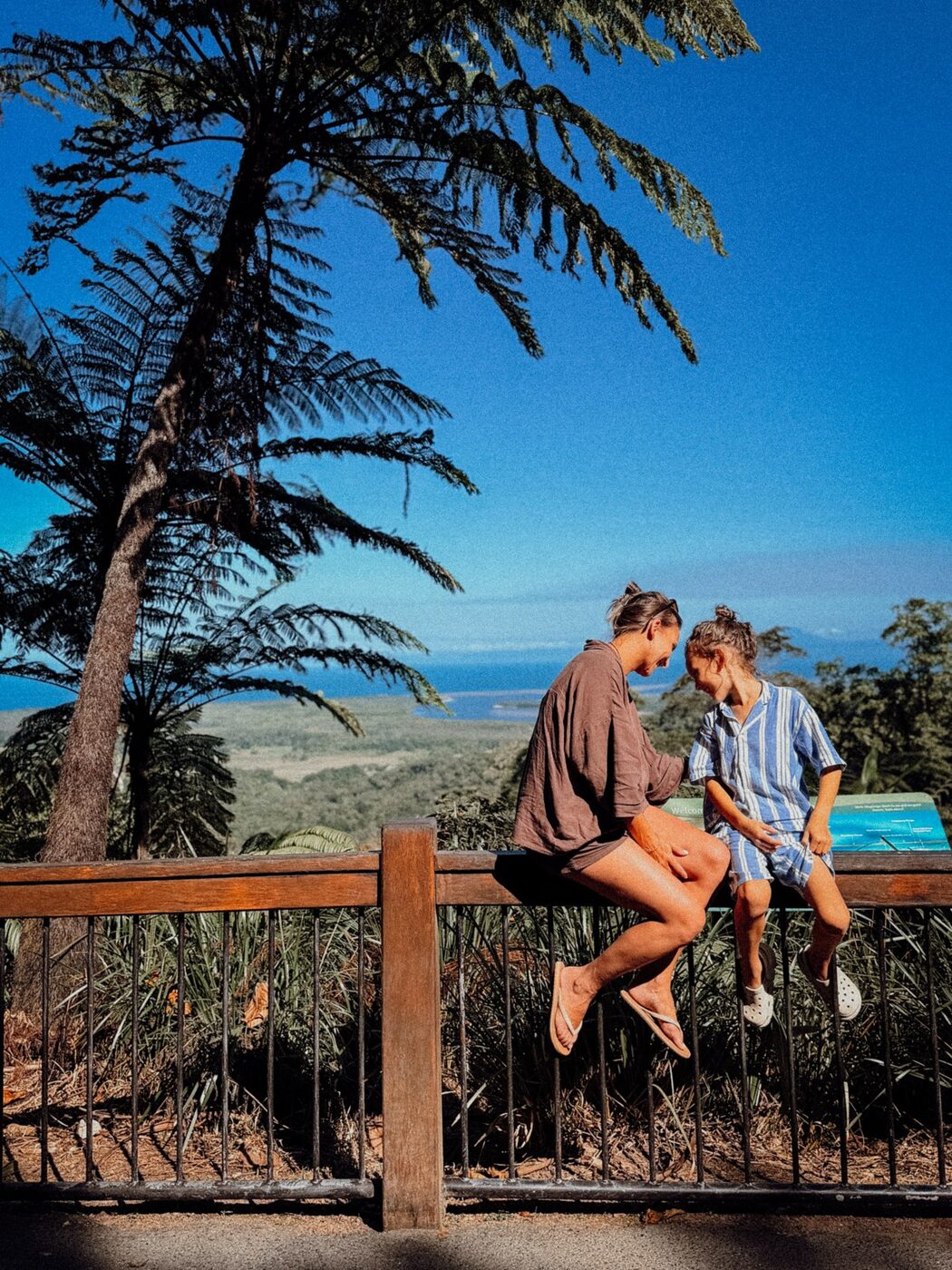 Jenn and her son sitting on a bench overlooking the coast